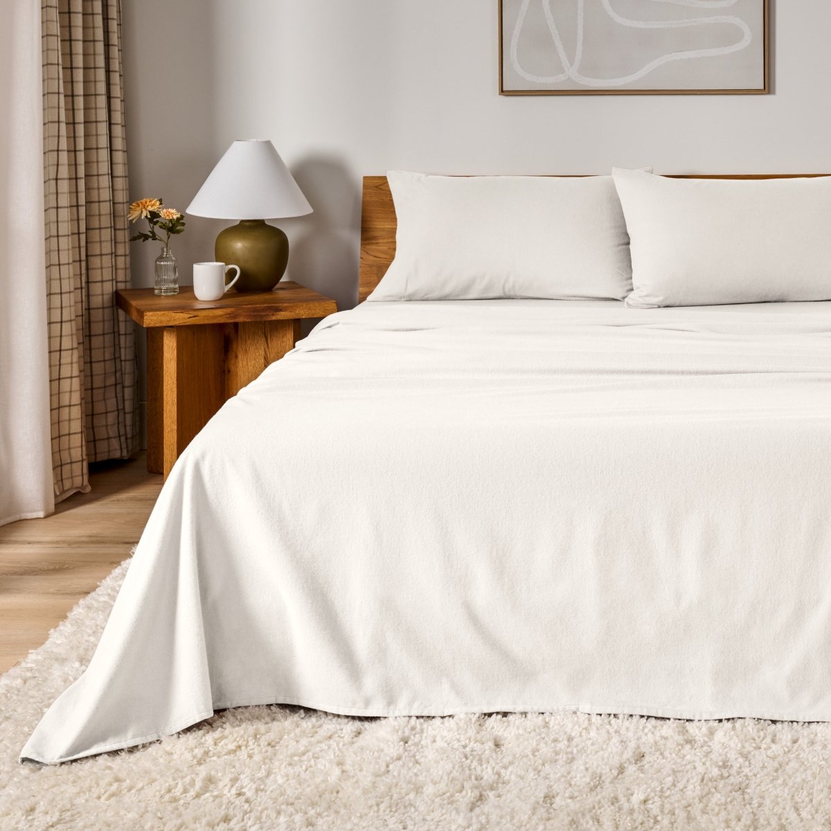 Cotton flannel sheet set on a bed in a bedroom setting with a lamp and decor.