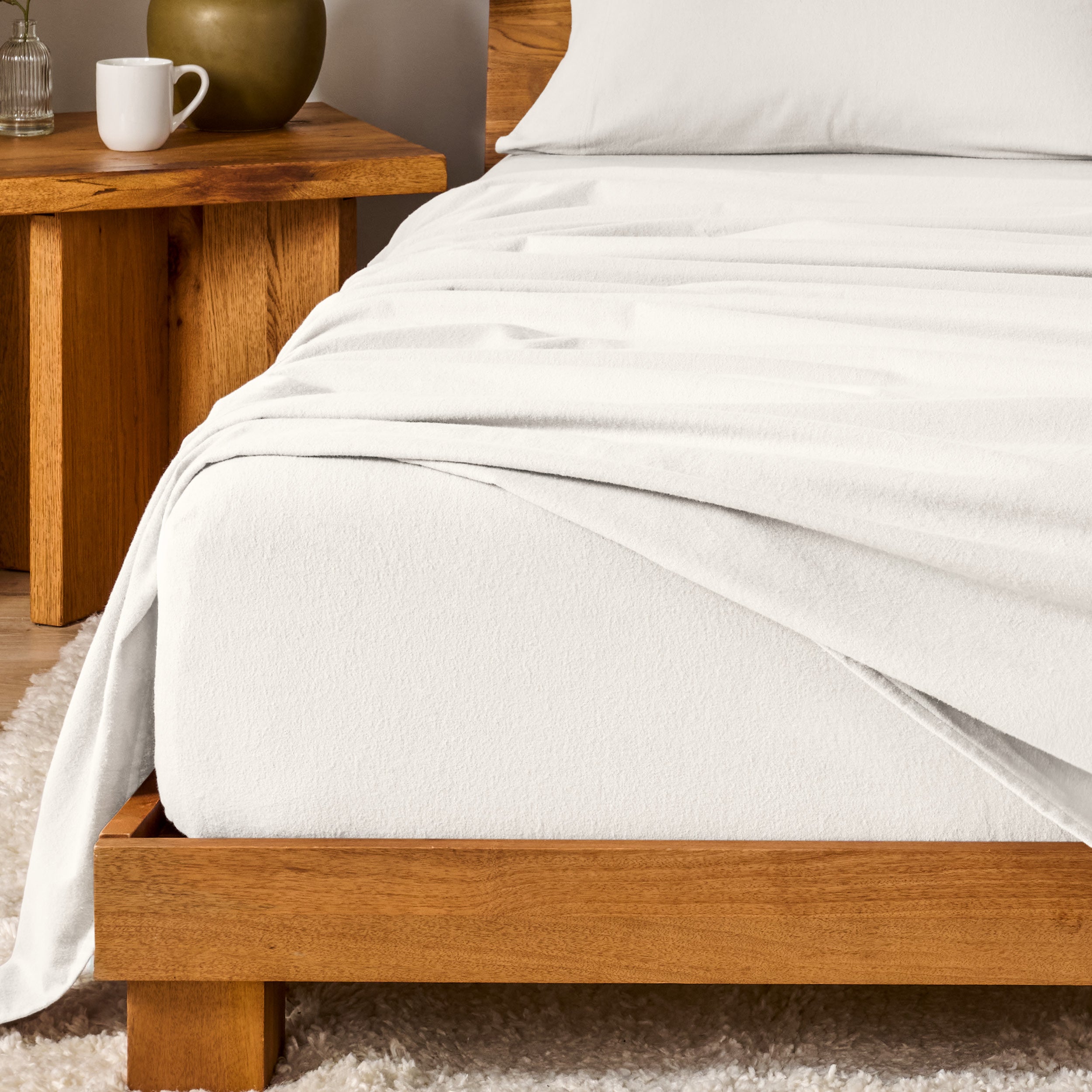 Bed with flannel bedding and wooden headboard and nightstand next to it.