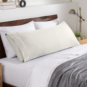 Bed sheets and pillows on a neatly made bed with a wooden headboard.