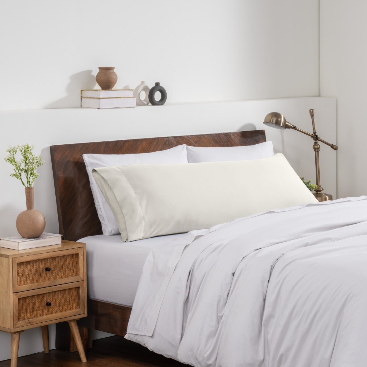 Bedroom with a wooden headboard and white bedding, featuring a nightstand and decorative items.