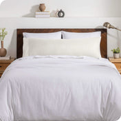 A body pillow cover on a pillow on a bed with other pillows and a duvet cover