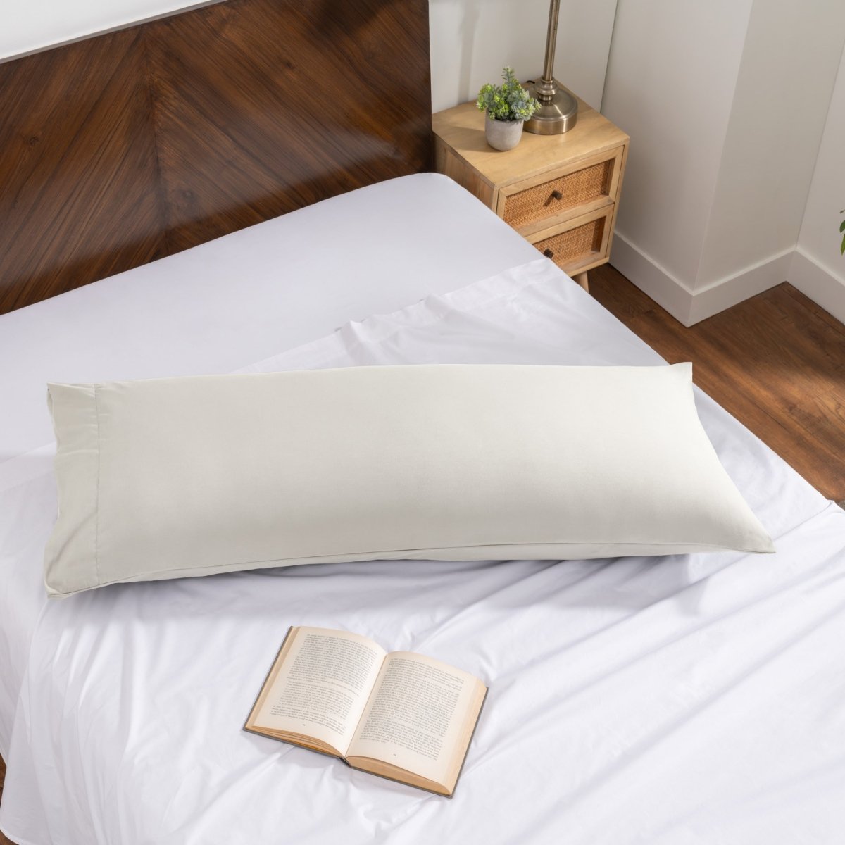 Pillowcase on a body pillow with a wooden headboard and plant in the background