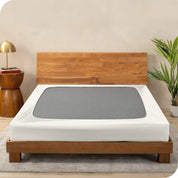 A cover on a box spring set on a wooden bed frame