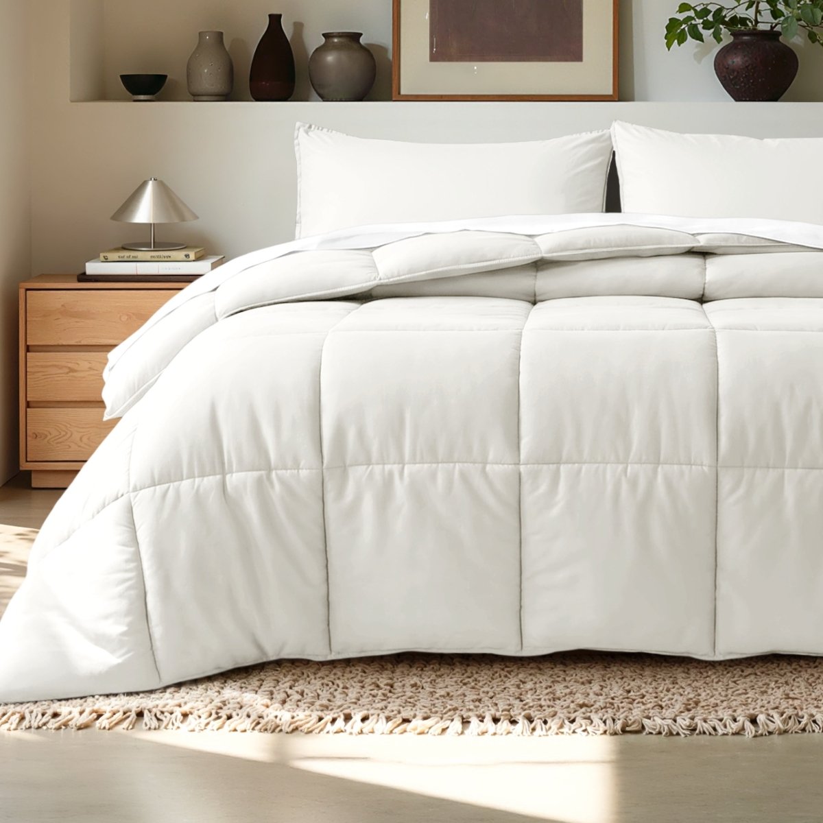Comforter on a bed in a bedroom setting with a wooden nightstand and decorative items.