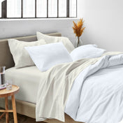 A modern bed made with a microfiber sheet set and duvet set. The duvet set and sheet set are folded over part way down the bed.