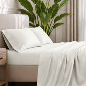Ultra-soft sheets and pillowcases on a bed with a plant in the background