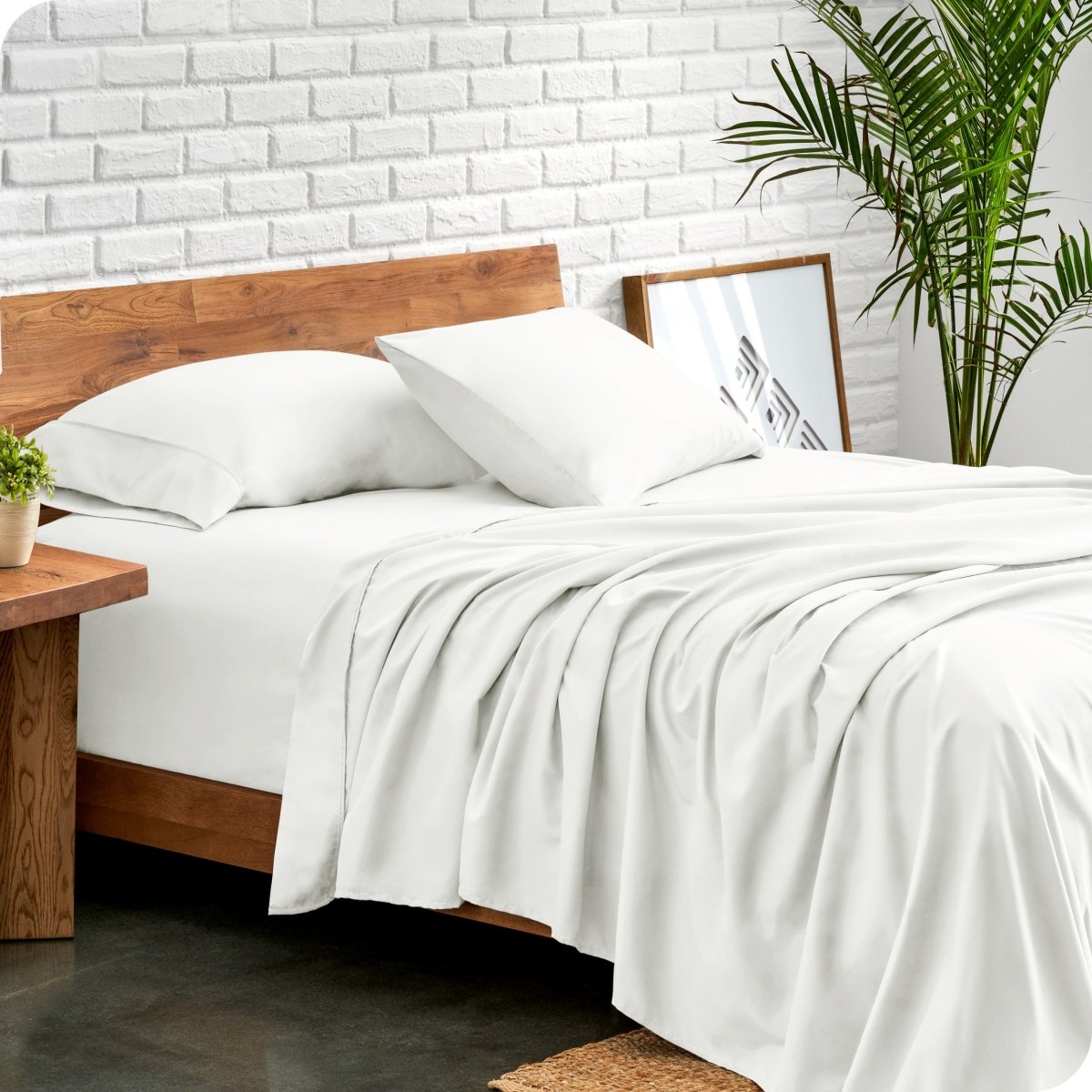 Bed with microfiber sheets against a white brick wall