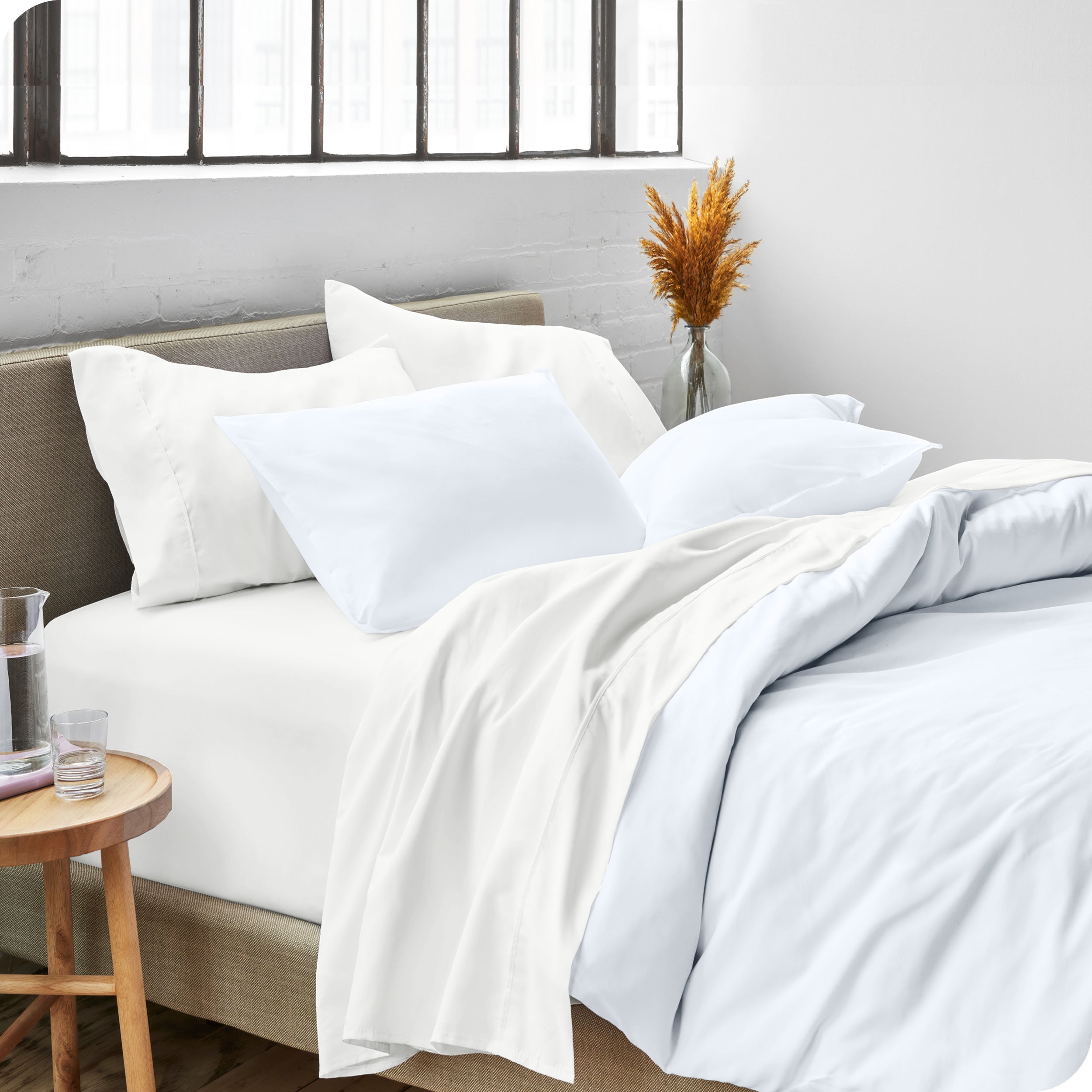 A side view of a bed made with microfiber sheets and a white duvet cover