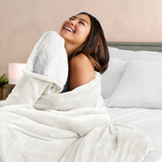 A woman smiling while wrapped in a sherpa blanket