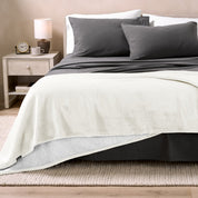 Bed with grey sheets and a sherpa blanket