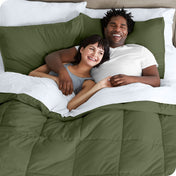 A couple is lying in bed with a comforter and sheets over them