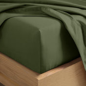 A close-up of a fitted sheet covering the corner of a bed frame, with matching top sheet draped over it.
