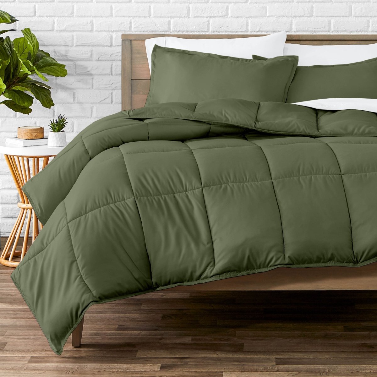 Comforter set on a bed with a white brick wall and plant in the background