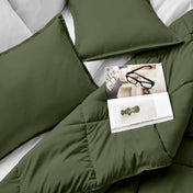Comforter and pillows on a bed with a magazine and glasses.