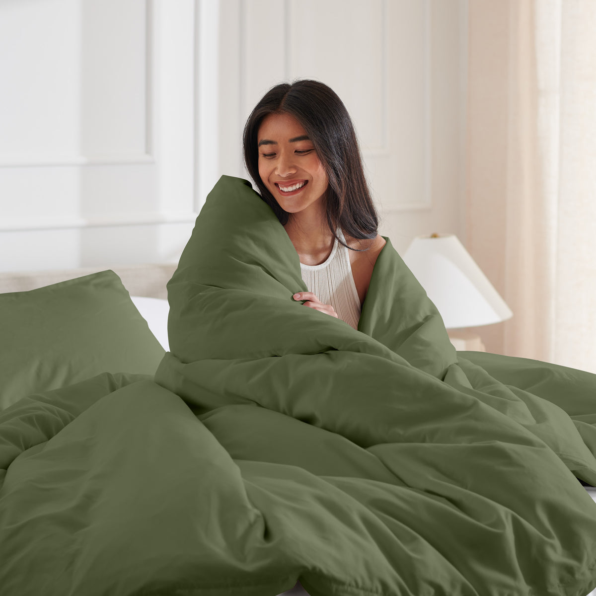 Woman smiling under duvet cover set in a bedroom setting
