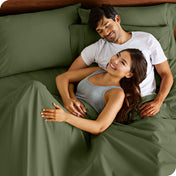 A couple is relaxing in bed with pillows behind them