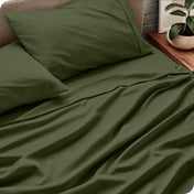 Bed sheets and pillows on a bed with a plant in the background