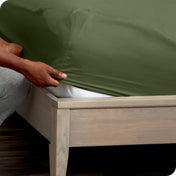 Person adjusting a fitted sheet on a mattress