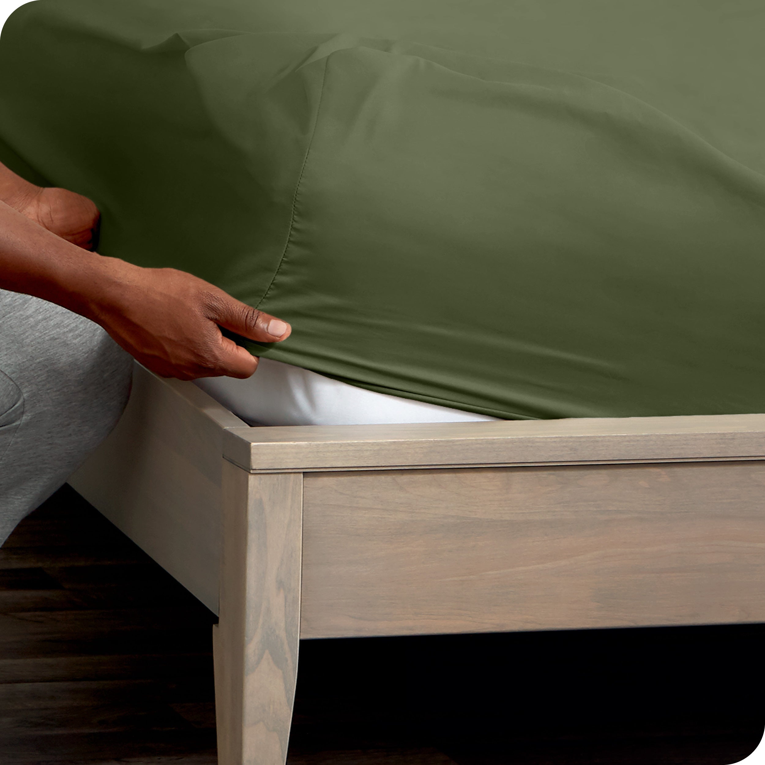 Person adjusting a fitted sheet on a mattress