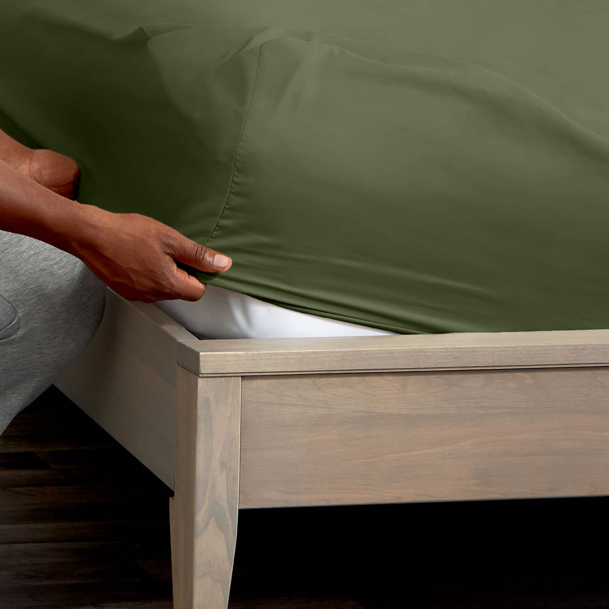 Person adjusting a fitted sheet on a mattress