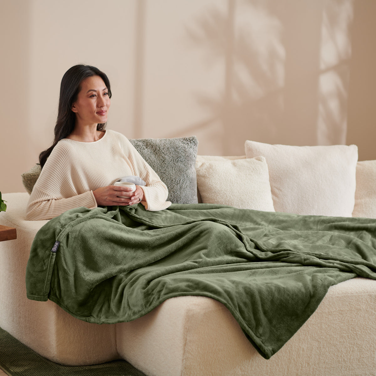 A woman sitting on a couch with a microplush blanket on her lap