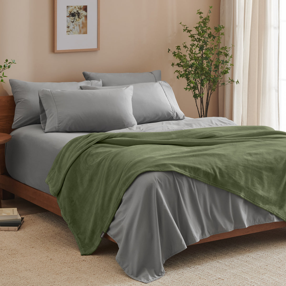 A bed made with grey sheets and a microplush blanket