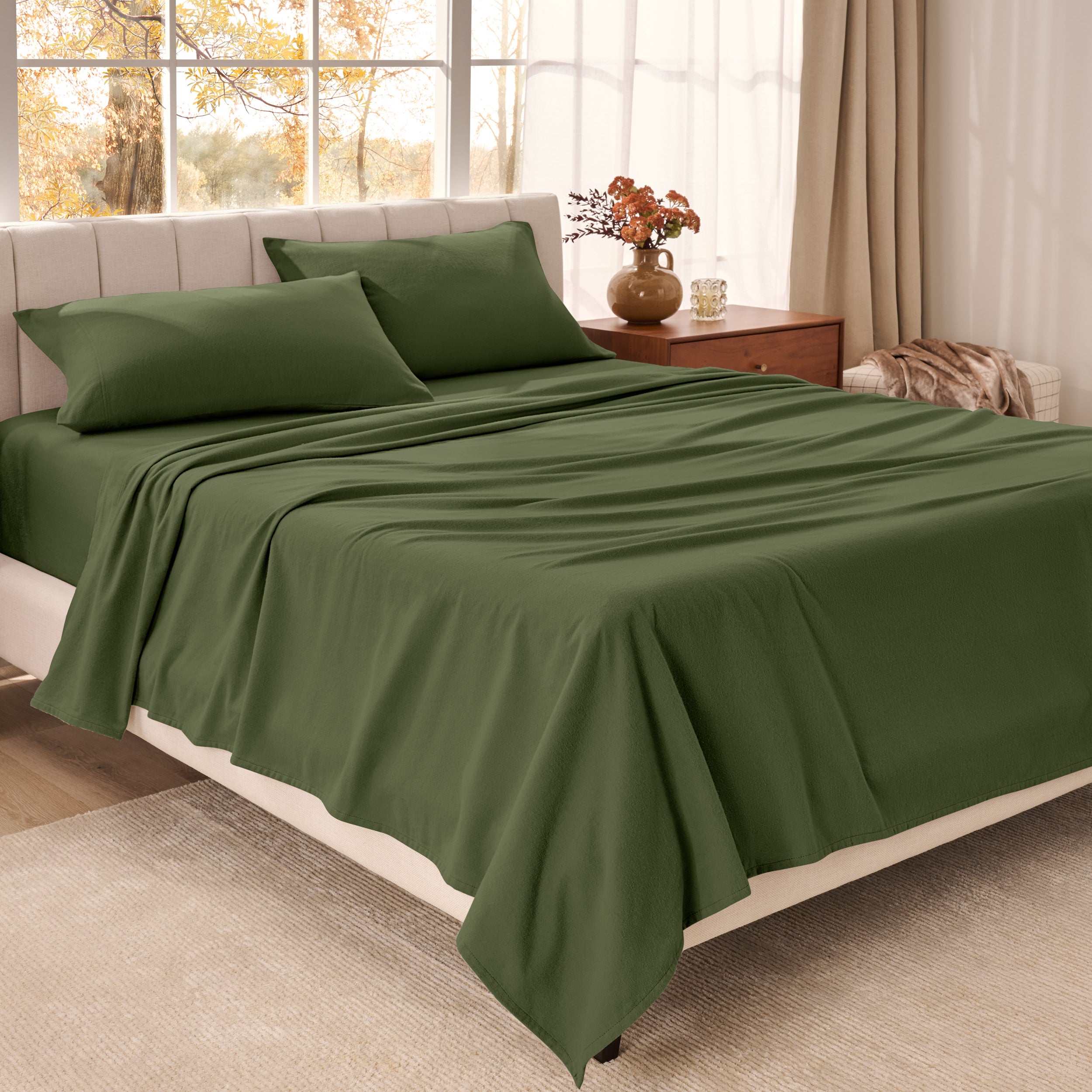 Bed sheets on a neatly made bed in a bright bedroom with large windows.