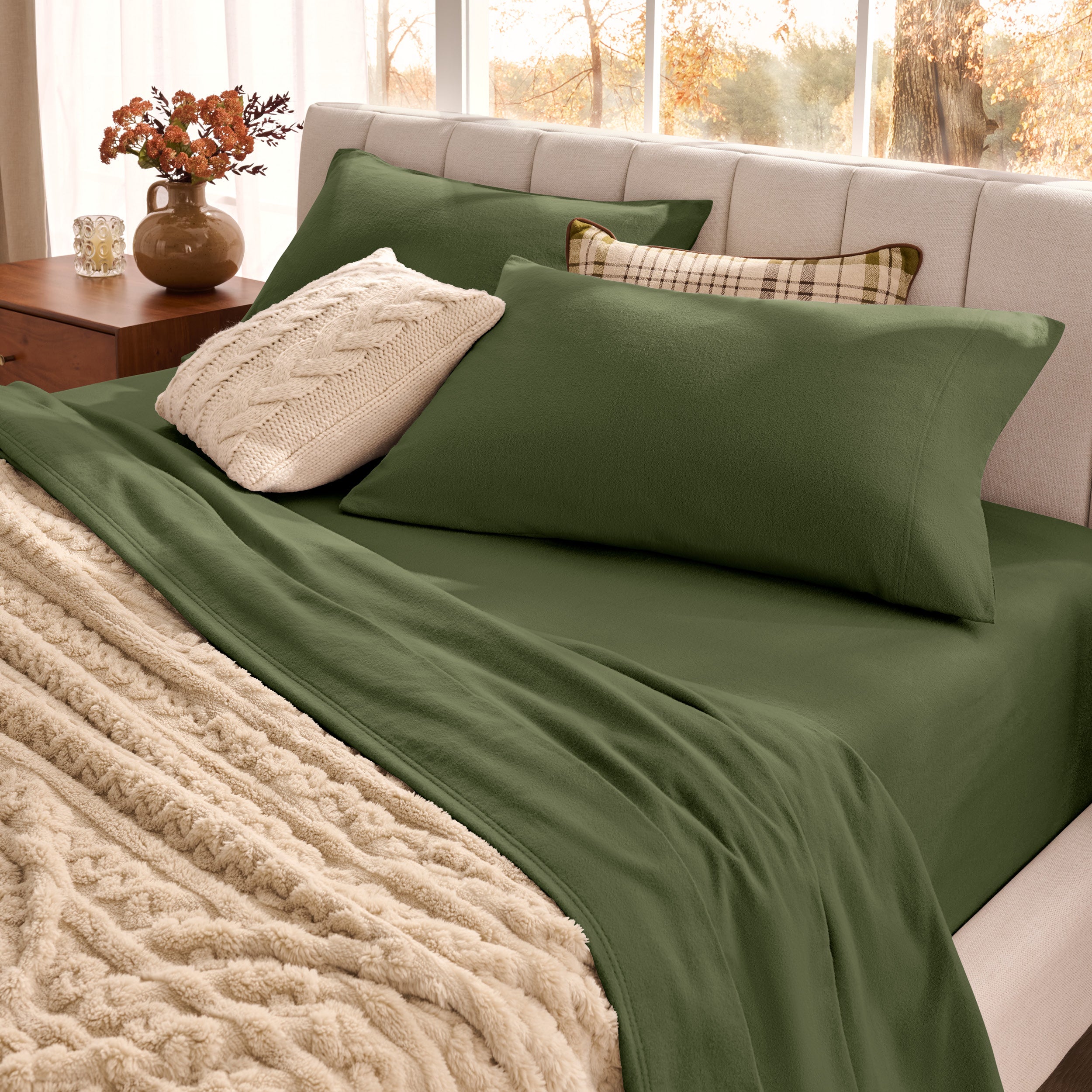 Neatly made bed with organic flannel sheets  and a beige blanket in a bright bedroom.