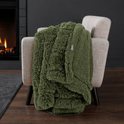 Sherpa blanket draped over an armchair in front of a fireplace.