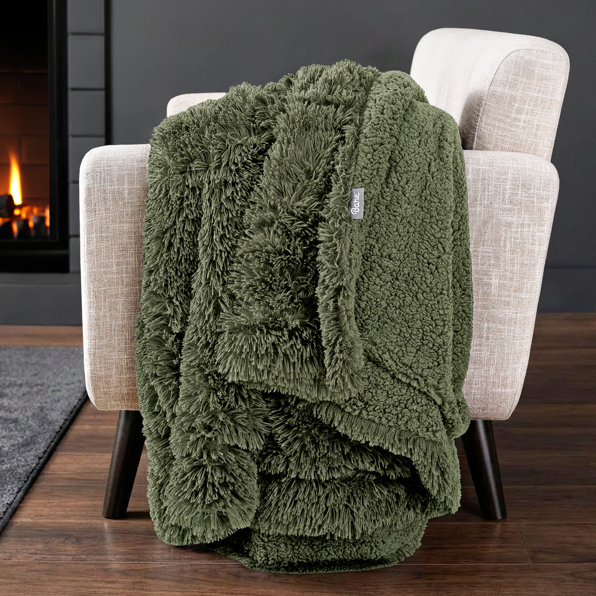 Sherpa blanket draped over an armchair in front of a fireplace.