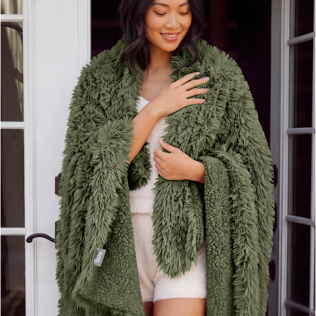 A woman standing with a shaggy blanket wrapped around her