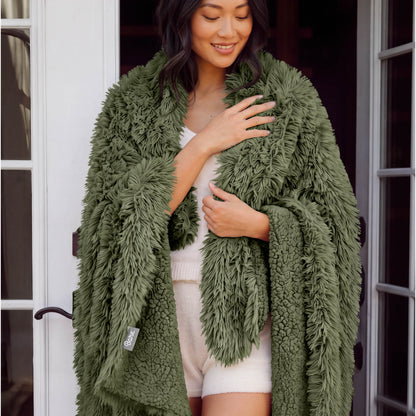 A woman standing with a shaggy blanket wrapped around her