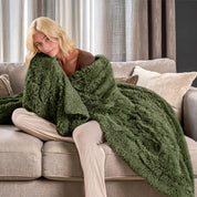 A woman sitting on a couch with a shaggy blanket wrapped around her