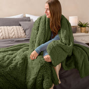 Fluffy blanket draped over a woman sitting on the end of a bed