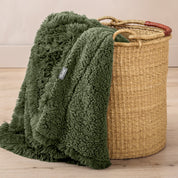 A blanket hanging over the edge of a wicker basket