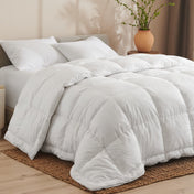 White down comforter on a bed with pillows and a plant in the background