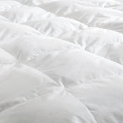 Close-up of a white down comforter with a soft texture.