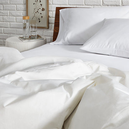 White bedding set on a bed with a nightstand in the background.