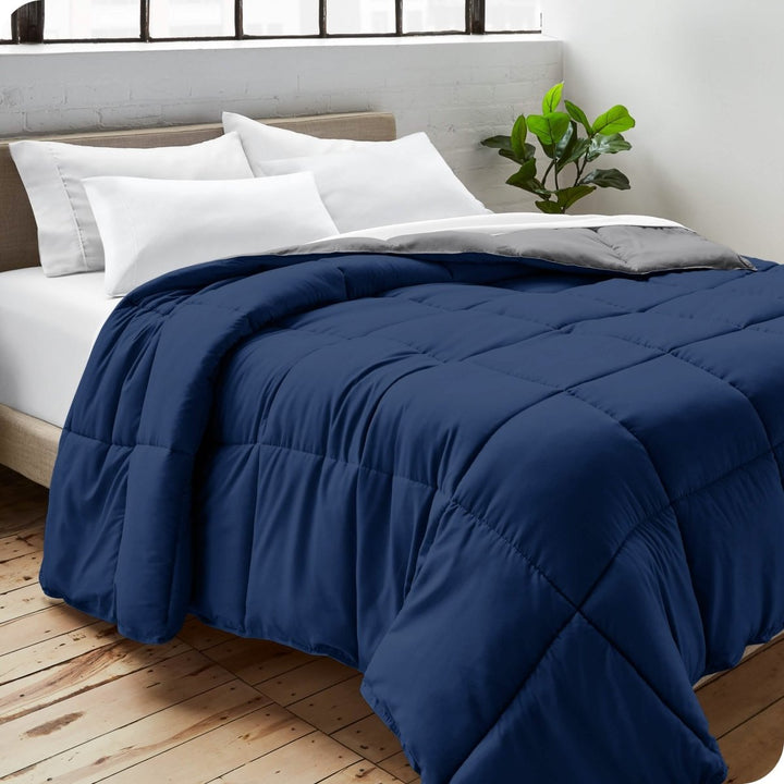 Close up of a comforter on a bed folded over itself. There are also 4 pillows on the bed.