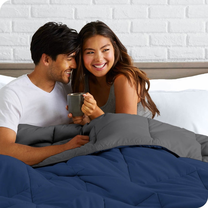 A couple sitting in bed with a reversible comforter over them