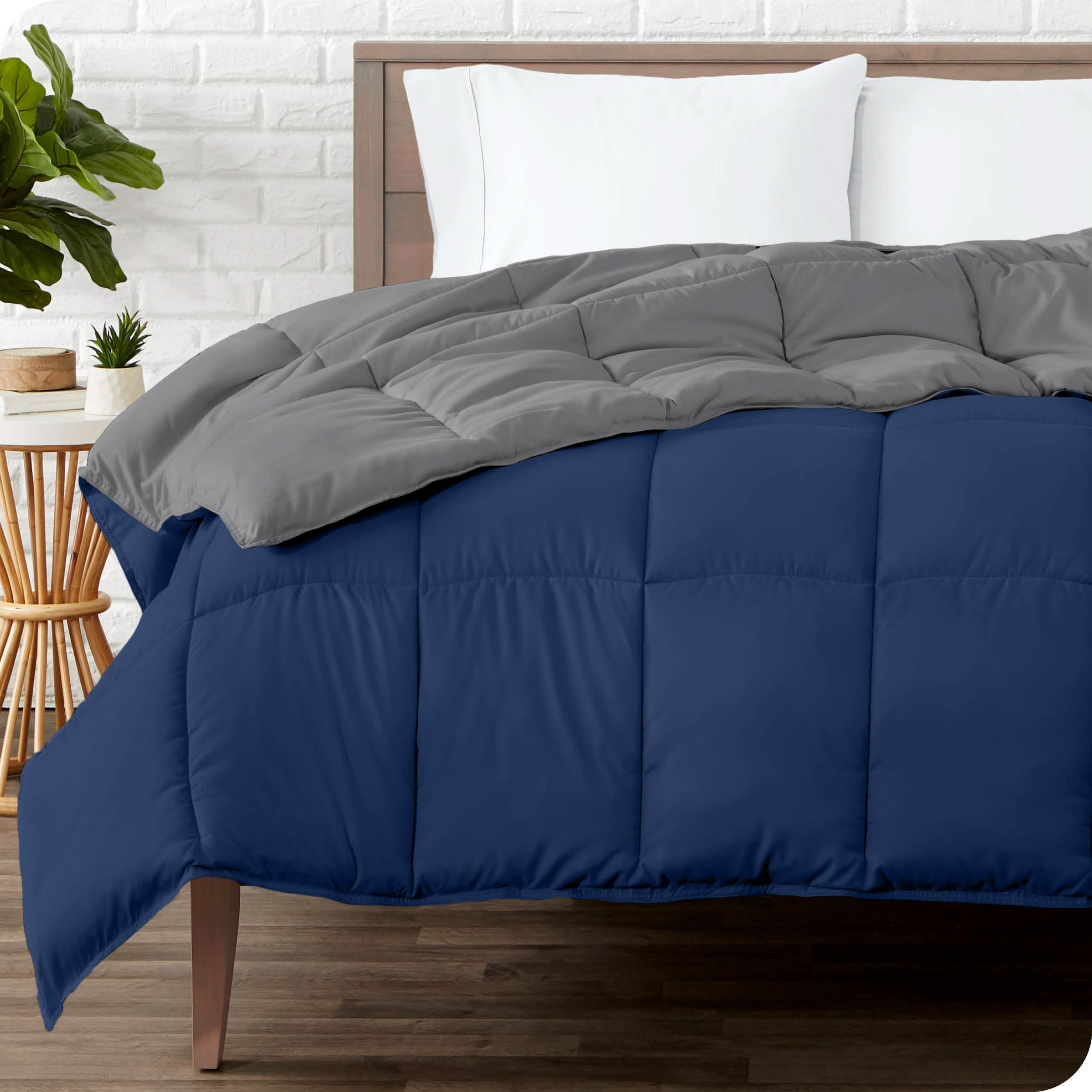 Wooden bed frame with a reversible comforter on the mattress. The comforter is folded back showing the two different colored sides.