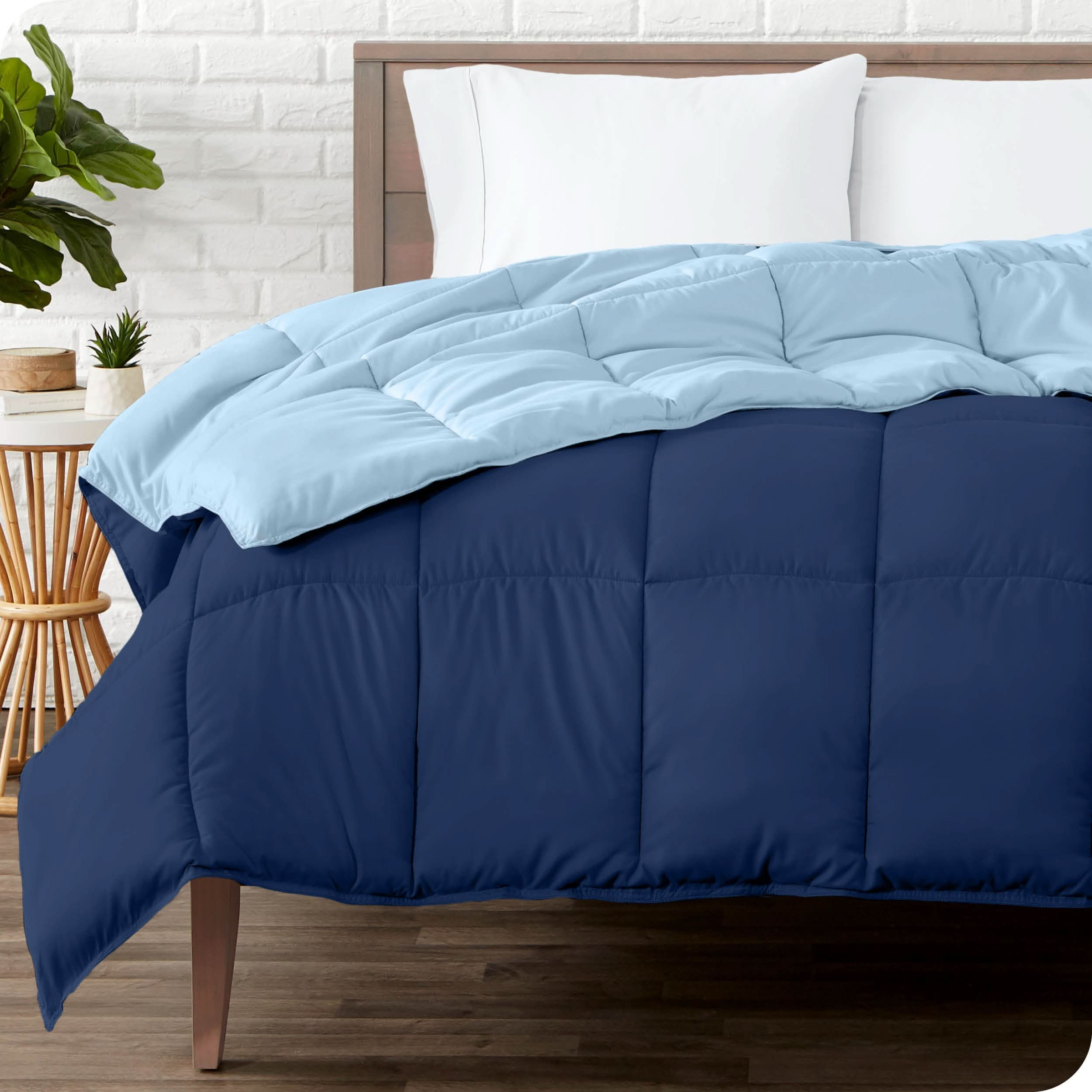 Wooden bed frame with a reversible comforter on the mattress. The comforter is folded back showing the two different colored sides.