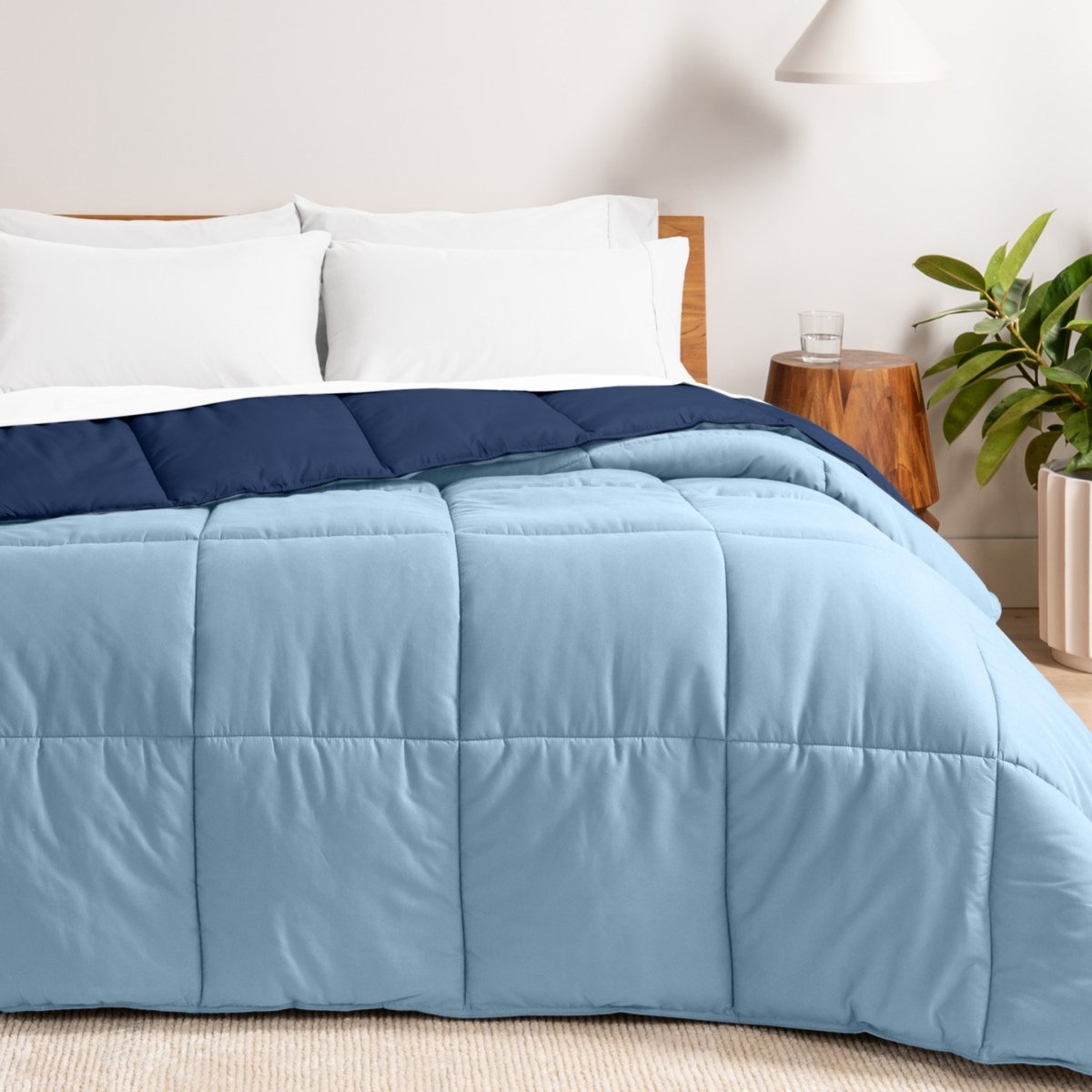 Bed with reversible comforter and white pillows in a bedroom setting
