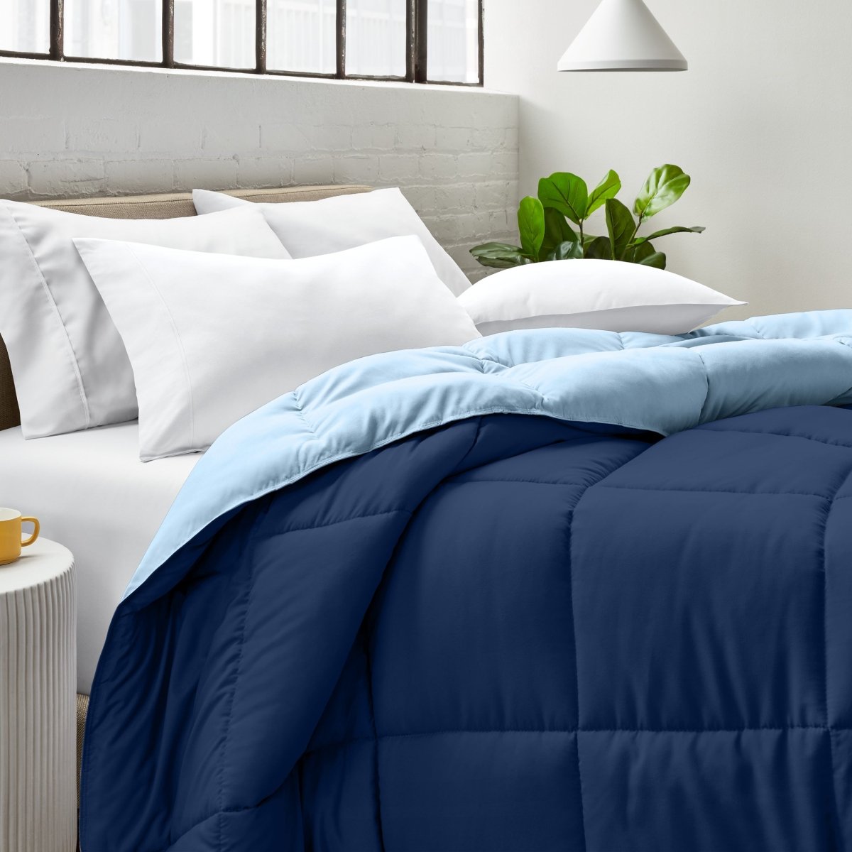 Bed with comforter and white pillows in a bright bedroom setting.