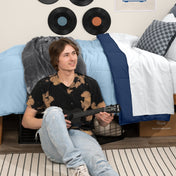 Person sitting on a bed holding a guitar in a bedroom setting with vinyl records on the wall.