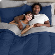 A couple is lying in bed with a comforter and sheets over them