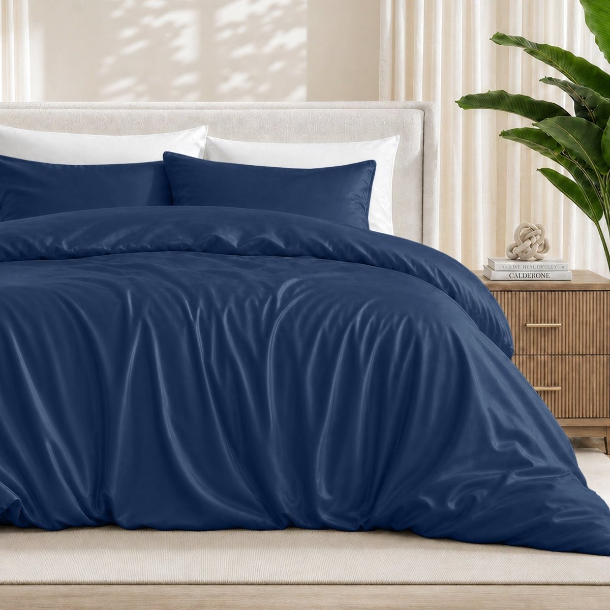 Dark blue duvet cover set on a bed in a bedroom setting with a plant and nightstand.