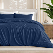 Dark blue duvet cover set on a bed in a bedroom setting with a plant and nightstand.