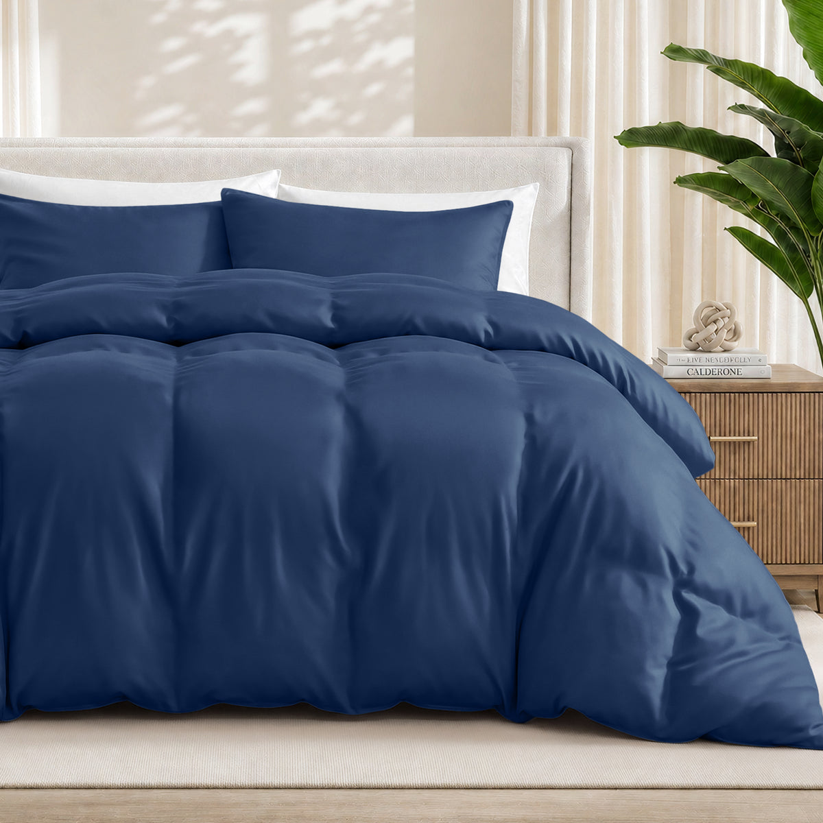Dark blue duvet cover set on a bed in a bedroom setting with a plant and nightstand.