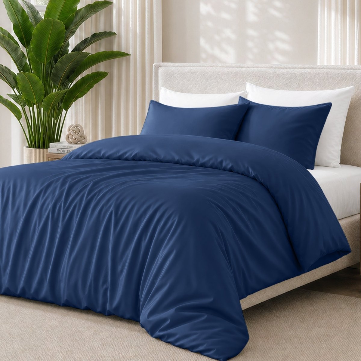 Dark blue bedding set on a bed with a plant in the background